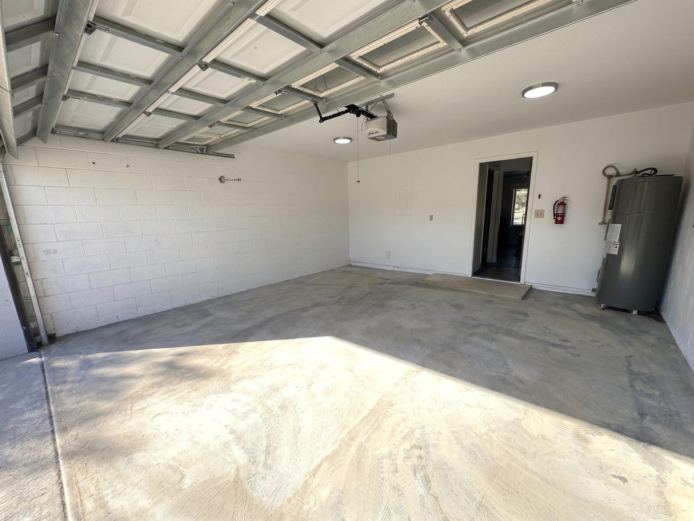 The same garage rebuilt: new ceiling, white painted block walls, new lighting and a clean slab